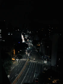 A nighttime cityscape with streetlights casting shadows on empty sidewalks.