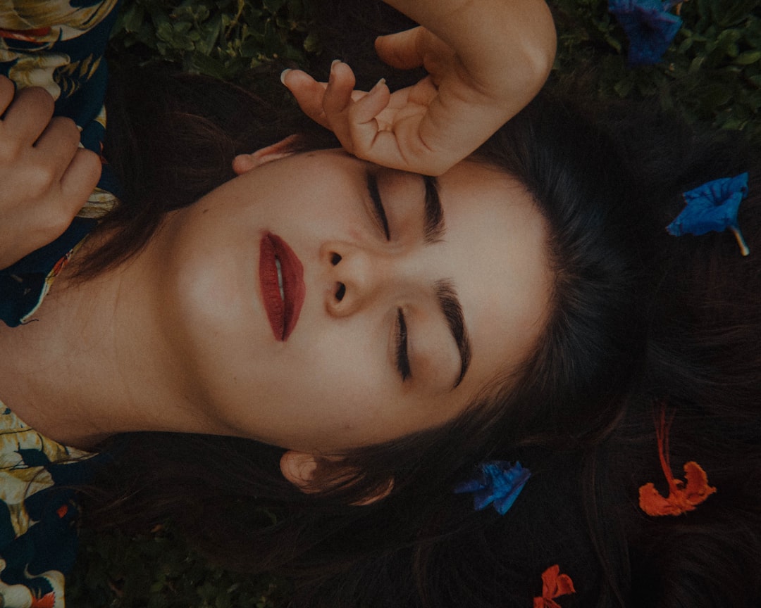 woman in red lipstick lying on green grass