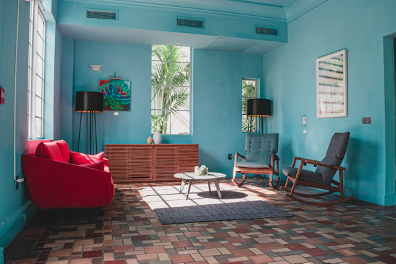A friendly painter discussing color options with a homeowner in a sunlit living room.