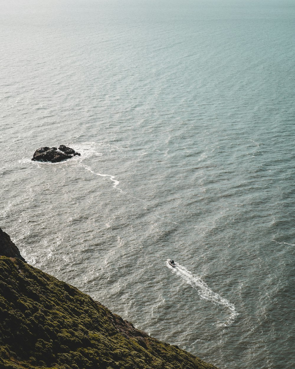 aerial view of ocean waves crashing on rock formation during daytime