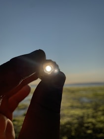 Hands holding a perfectly round ball against a clear blue sky background.