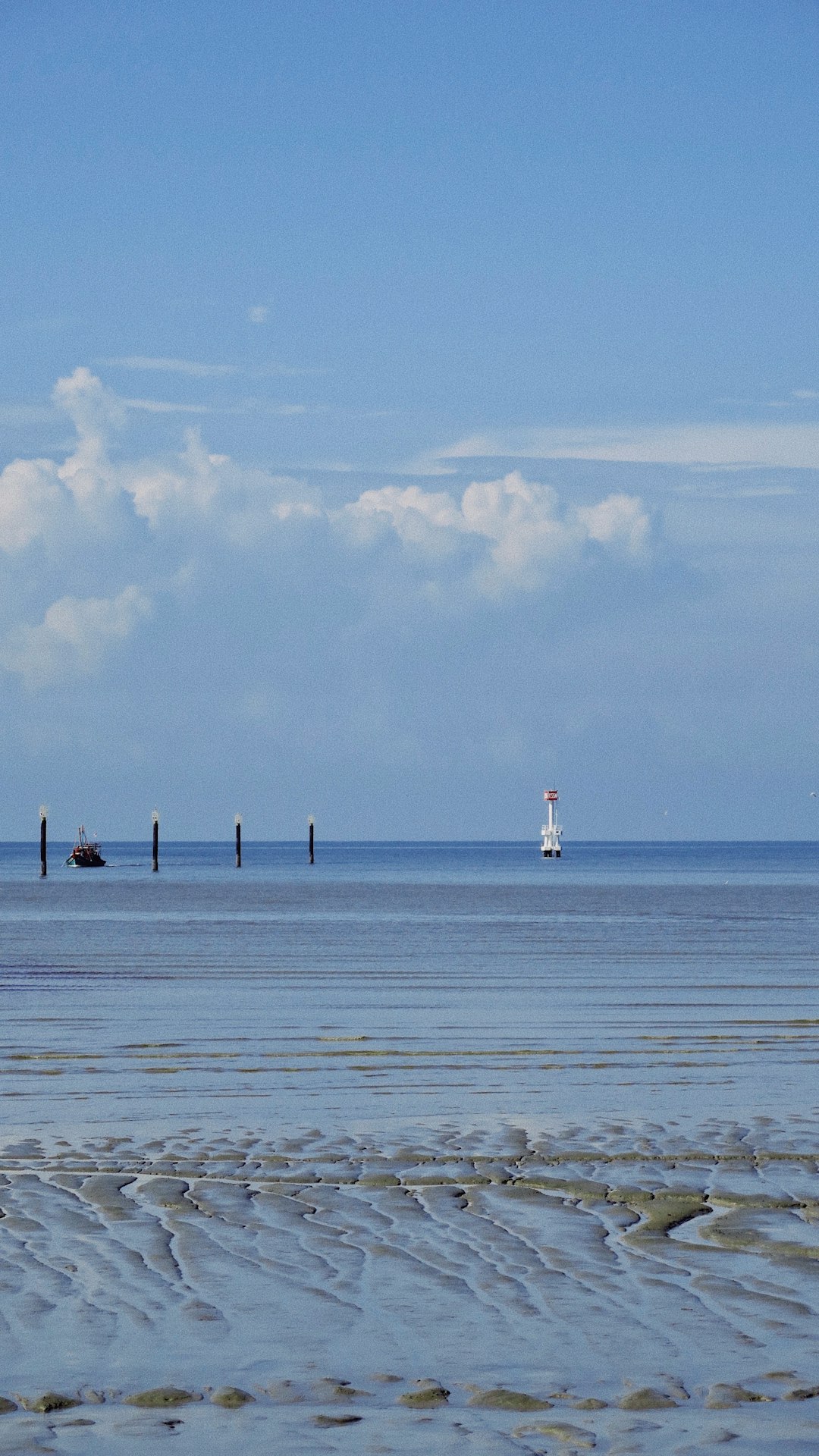 white and black lighthouse on sea under white clouds during daytime