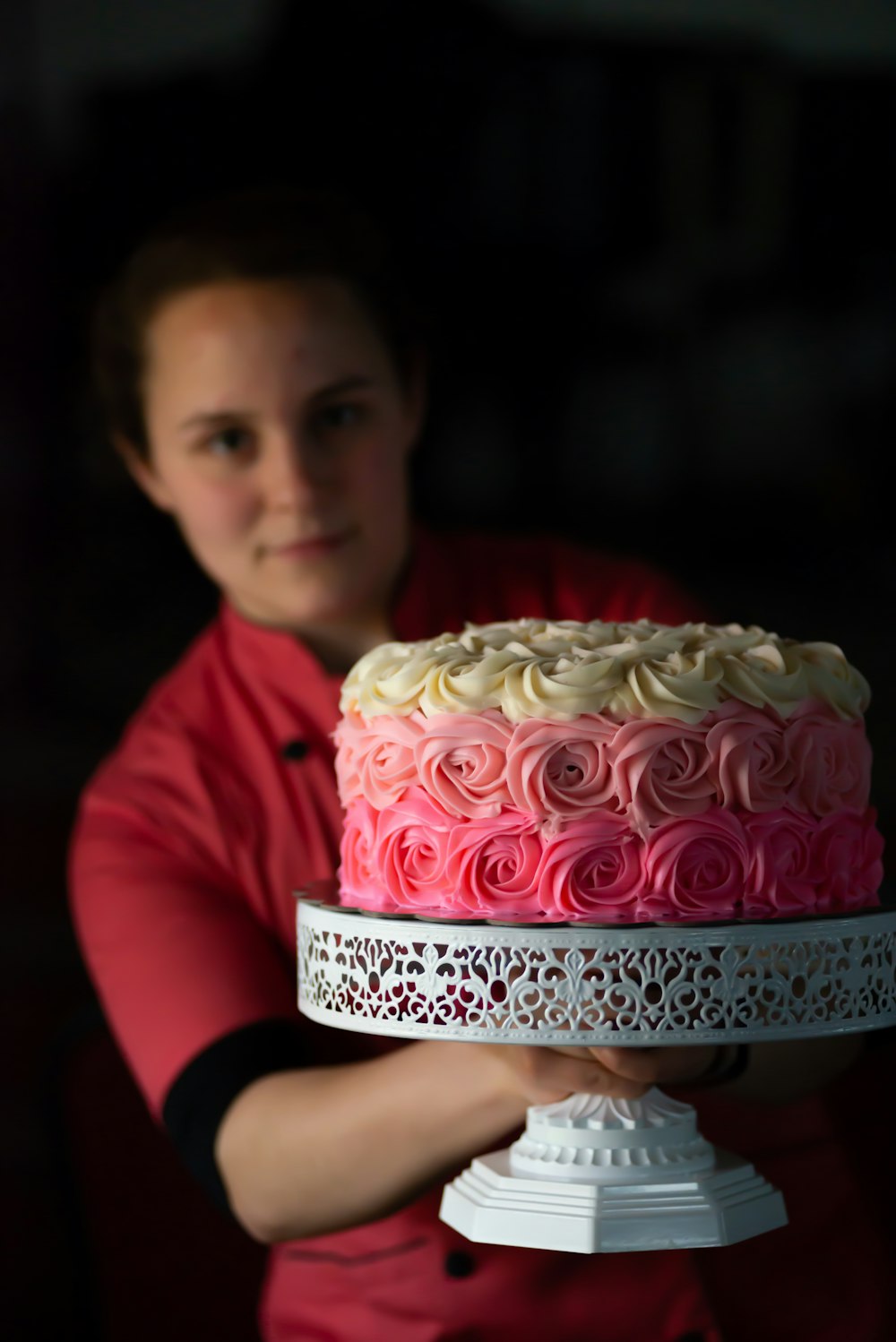 girl in red long sleeve shirt holding pink and white cake