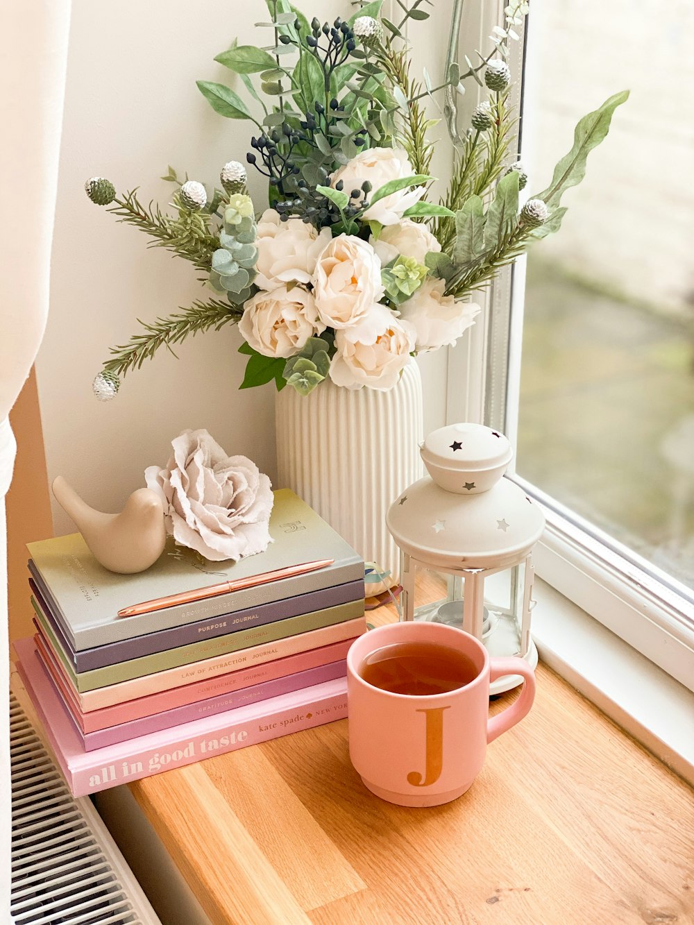 white ceramic rabbit figurine on book beside brown ceramic mug