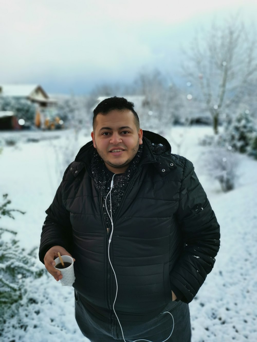 man in black jacket holding white ceramic mug