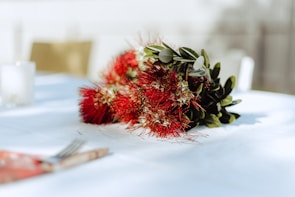 Close-up of deep red flowers and satin ribbons decorating a wedding table.