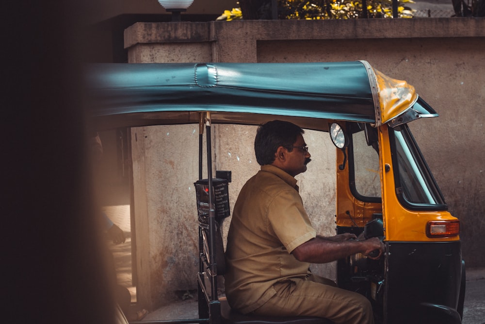 homme en chemise marron assis sur un pousse-pousse automatique bleu et jaune