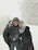 woman in black jacket and gray knit cap standing on snow covered ground during daytime