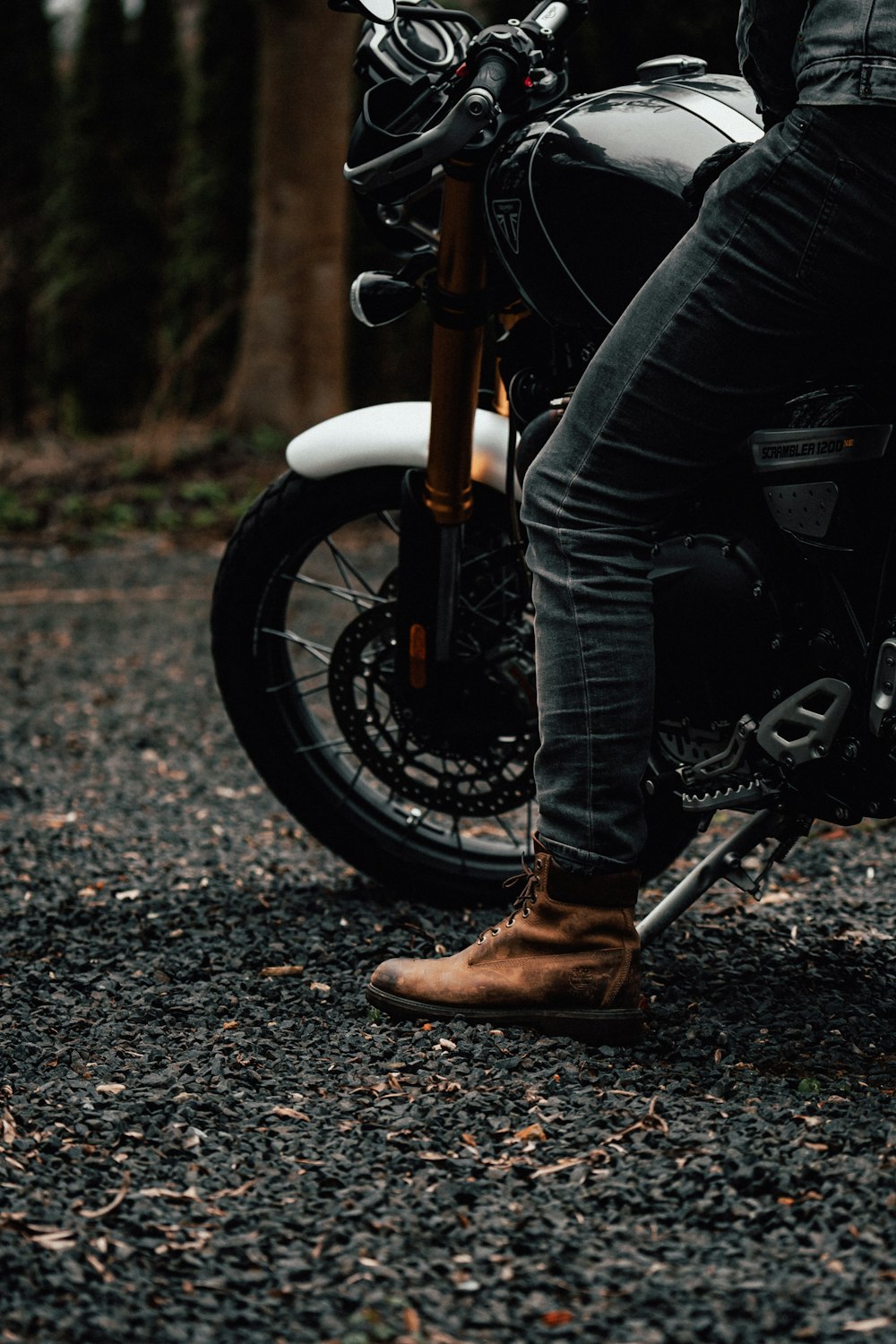 person in black jacket and blue denim jeans riding on motorcycle