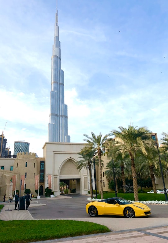 people walking on street near white concrete building during daytime in The Dubai Fountain United Arab Emirates