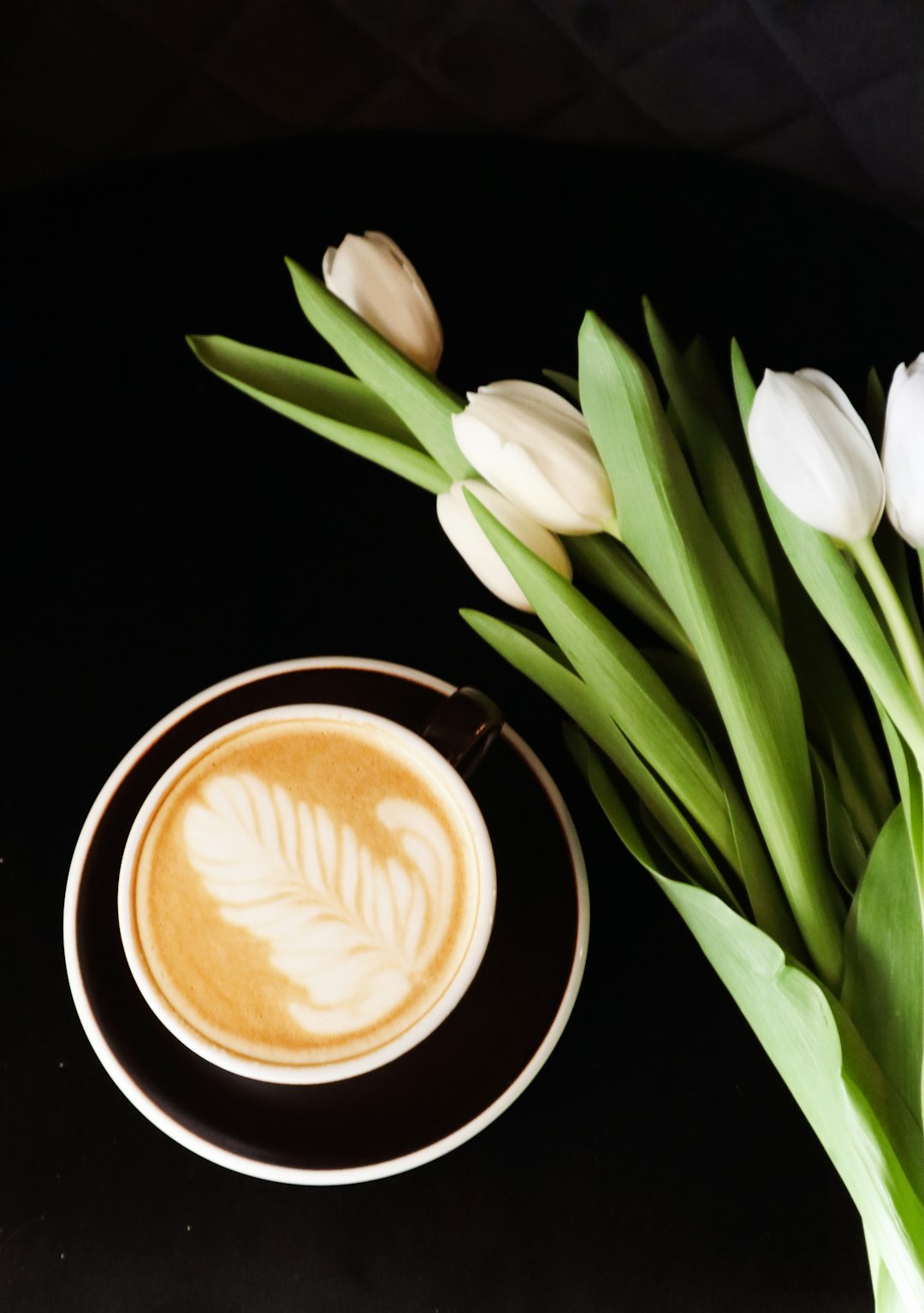 white tulips beside brown ceramic mug with coffee