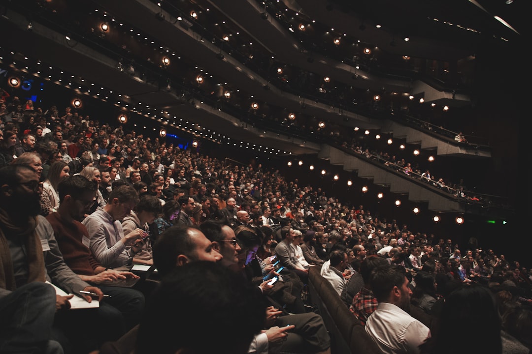 people sitting on chairs inside stadium, Audience in a large theater or auditorium