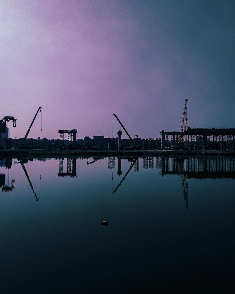 silhouette of dock on body of water during night time