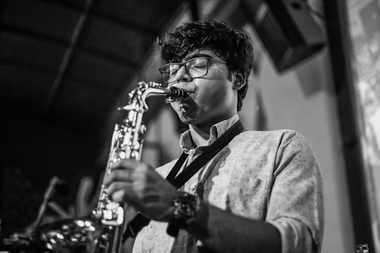 Close-up of a saxophonist deeply immersed in his solo, with a blurred audience in the background.