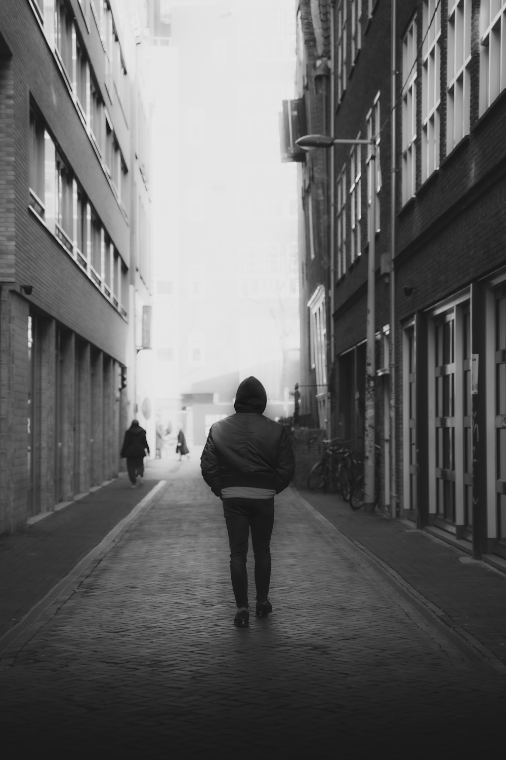 man in black jacket walking on sidewalk during daytime