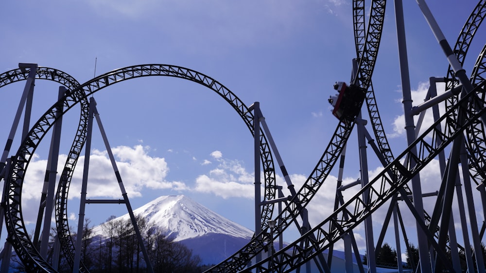 black roller coaster over the mountain during daytime