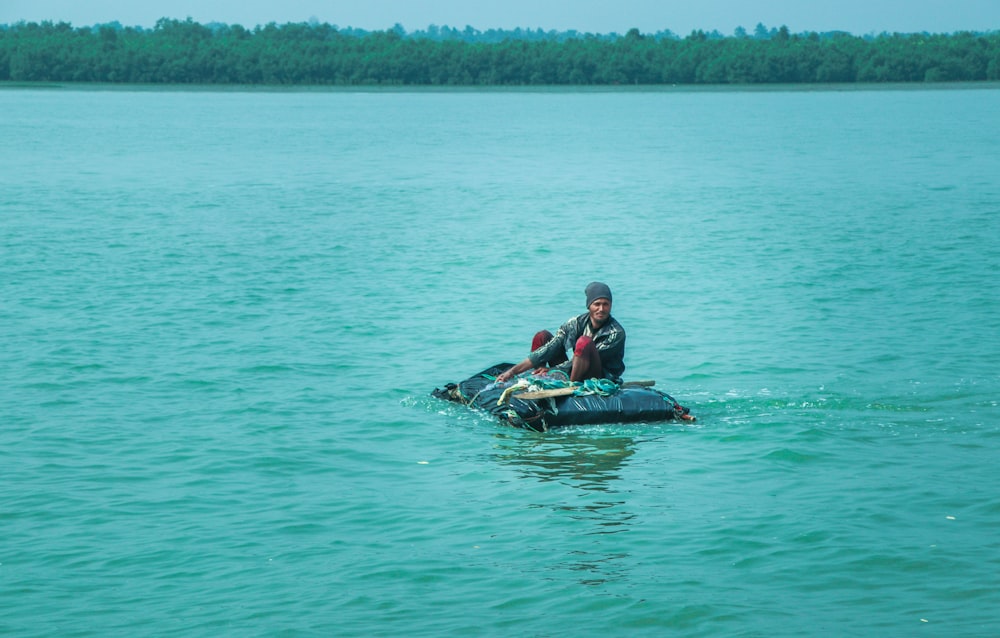 man in blue shirt riding on blue kayak on body of water during daytime
