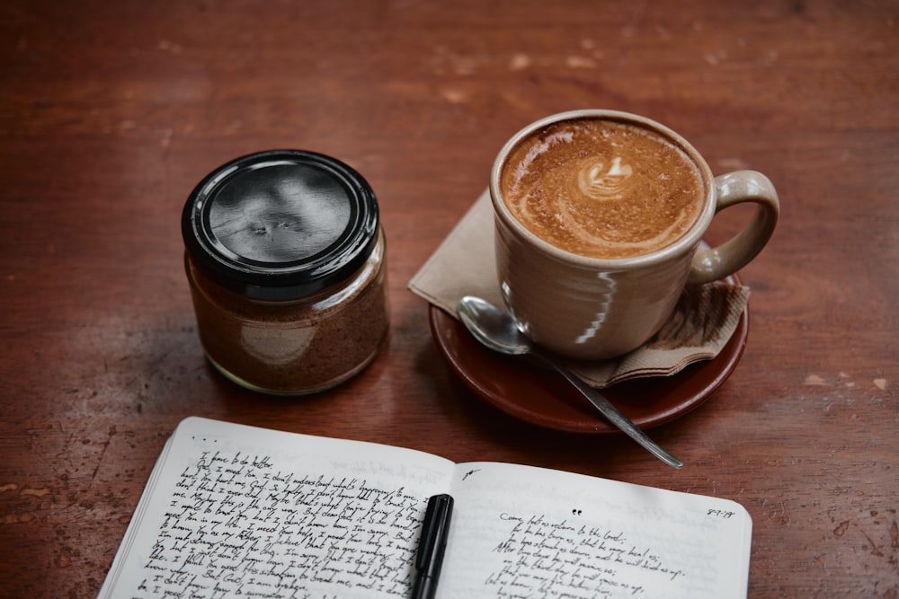 white ceramic mug on saucer beside silver spoon