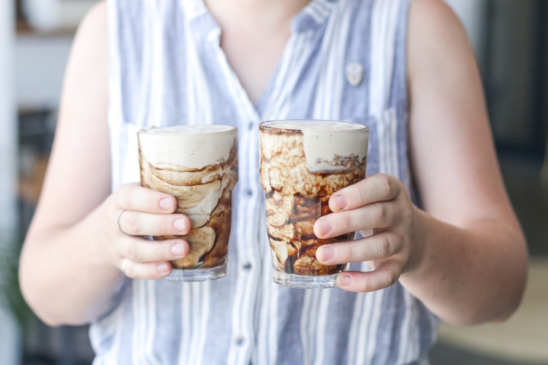 woman in white button up shirt holding clear drinking glass