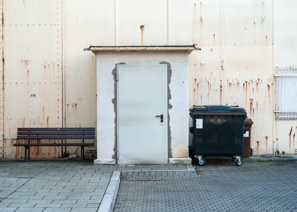 black trash bin beside white wall