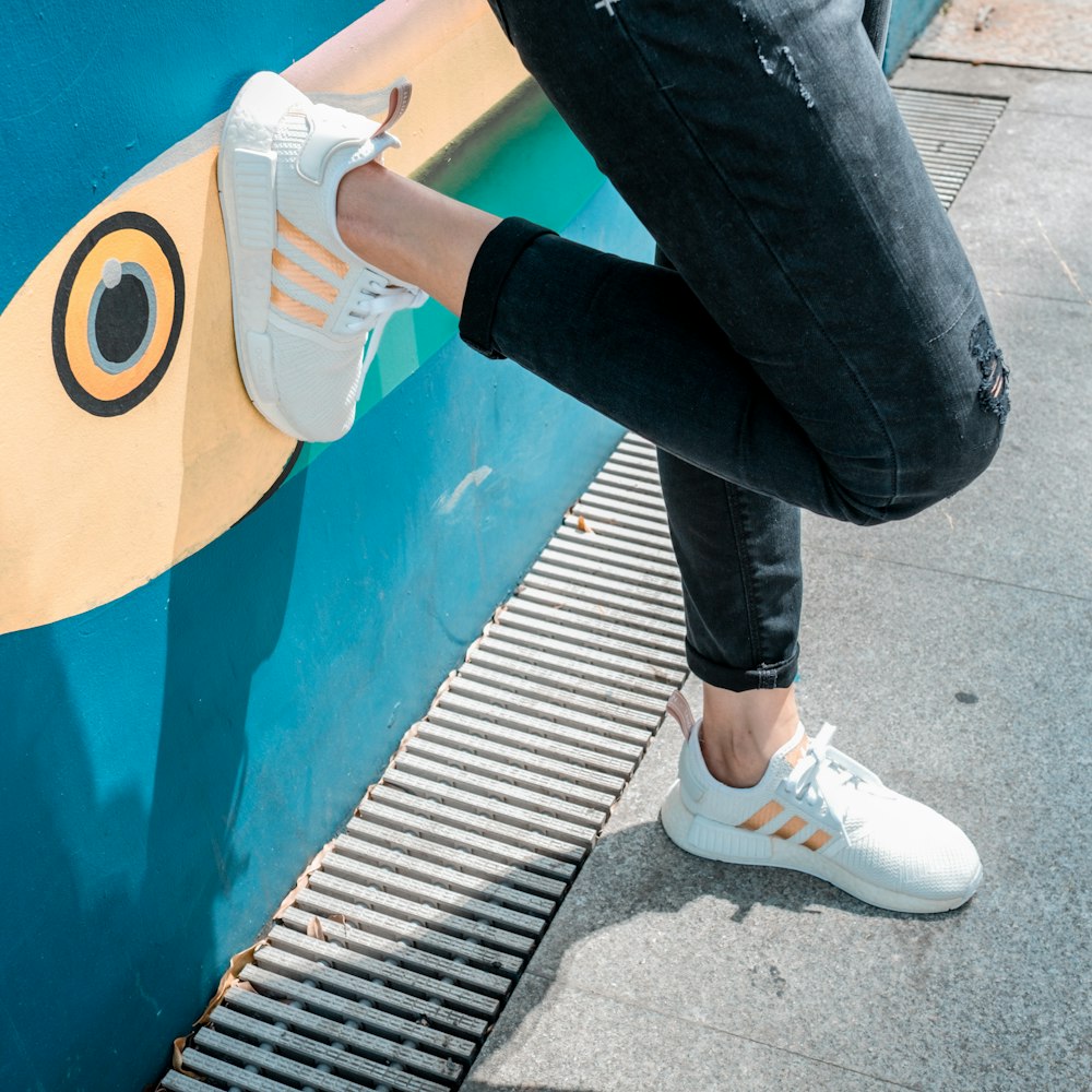 person in black denim jeans and white nike sneakers