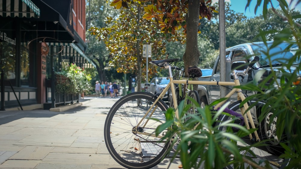 black bicycle parked beside green plants during daytime