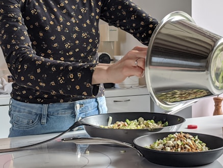woman in blue denim jeans holding stainless steel cooking pot