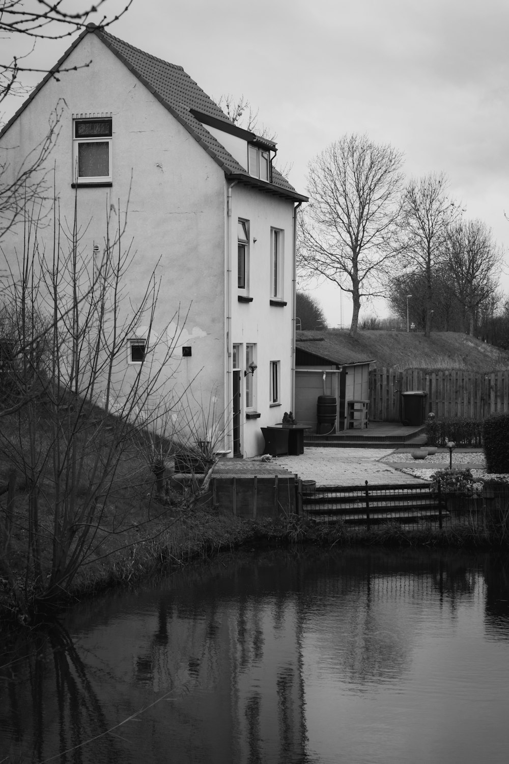 grayscale photo of house near body of water