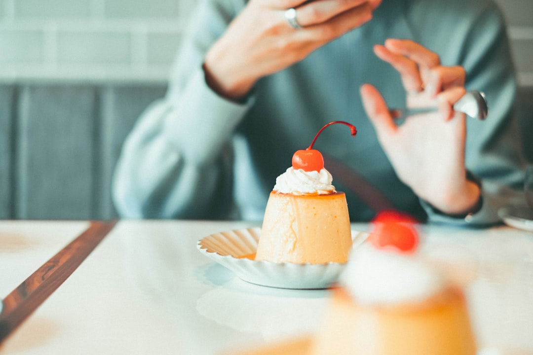 person holding cupcake with white icing on white round plate