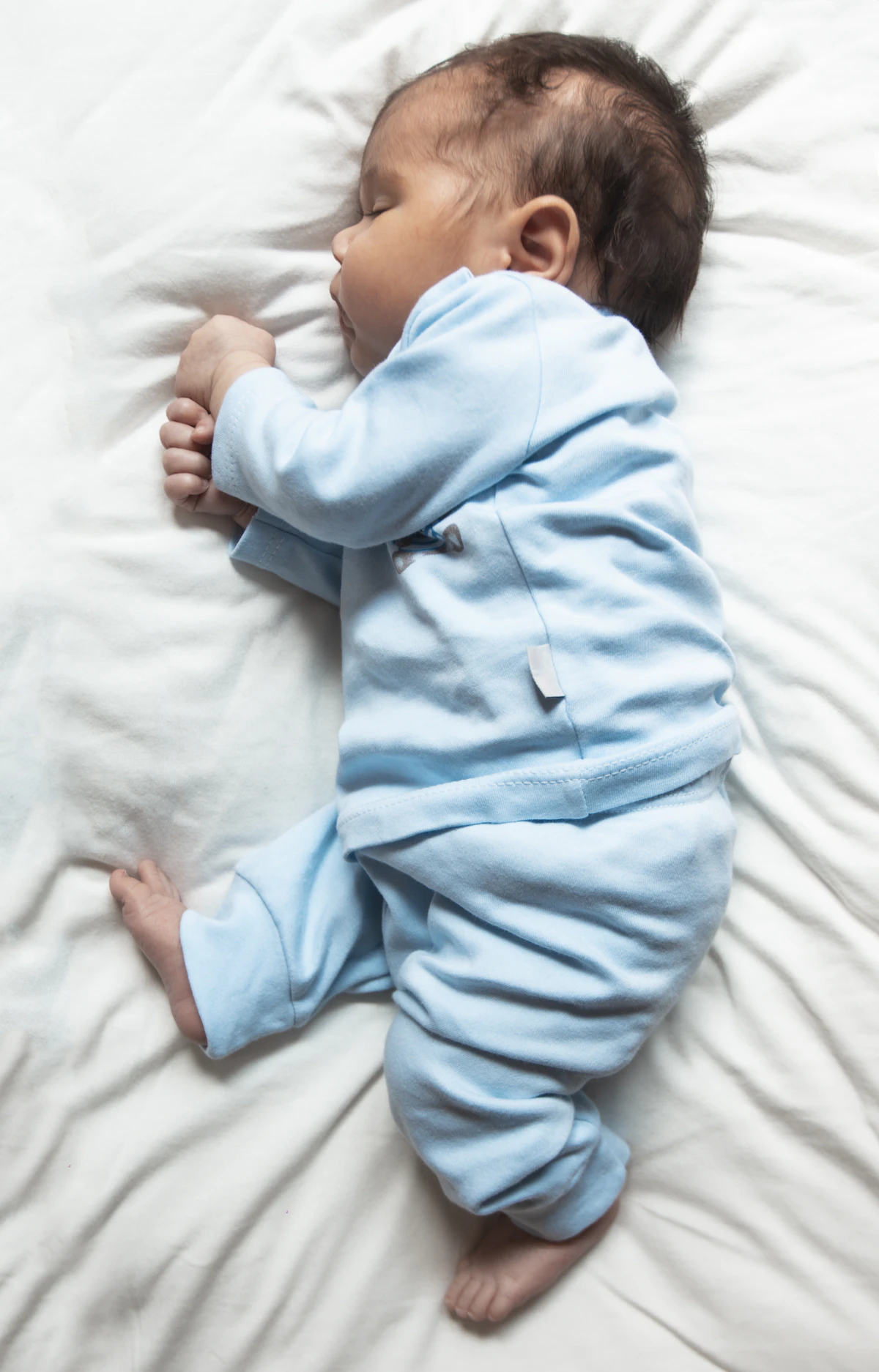 Peaceful newborn baby sleeping on a soft white surface
