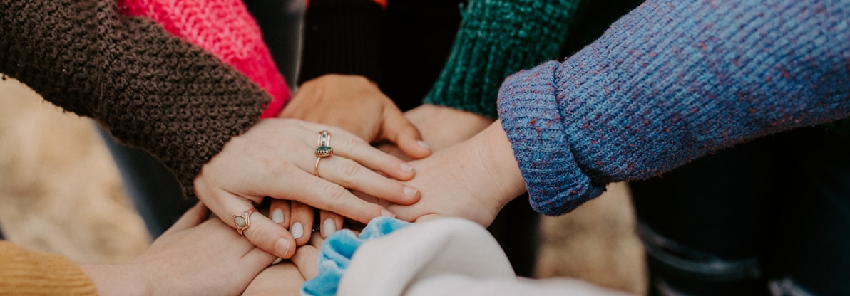 person in red sweater holding babys hand