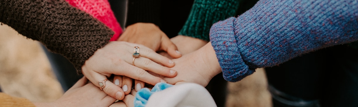 person in red sweater holding babys hand