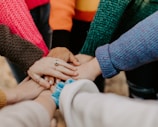 person in red sweater holding babys hand