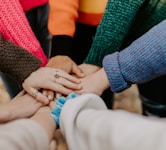 person in red sweater holding babys hand