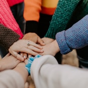 person in red sweater holding babys hand