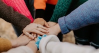 person in red sweater holding babys hand