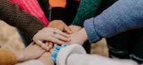 person in red sweater holding babys hand