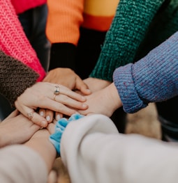 person in red sweater holding babys hand