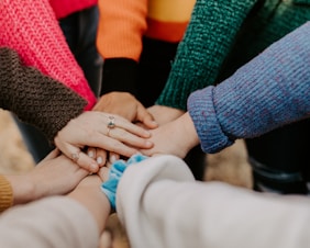 person in red sweater holding babys hand