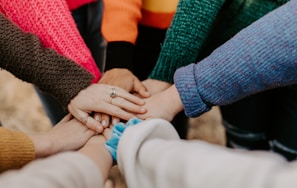 person in red sweater holding babys hand