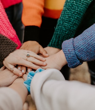 person in red sweater holding babys hand