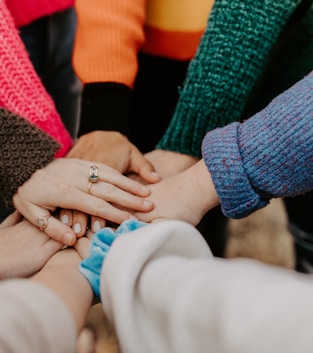 person in red sweater holding babys hand