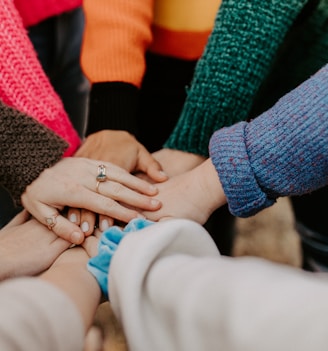 person in red sweater holding babys hand