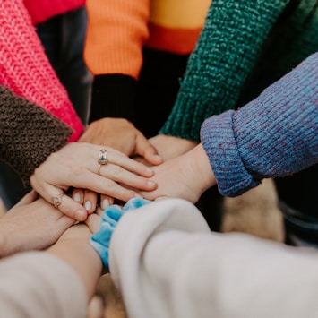 person in red sweater holding babys hand