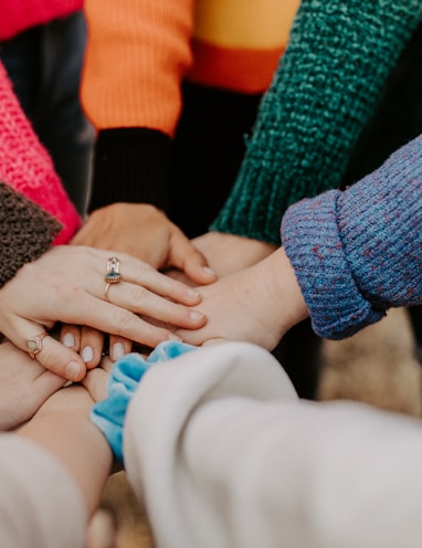 person in red sweater holding babys hand