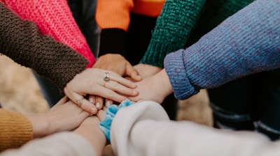 person in red sweater holding babys hand