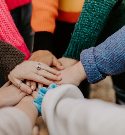 person in red sweater holding babys hand