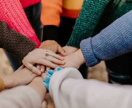 person in red sweater holding babys hand