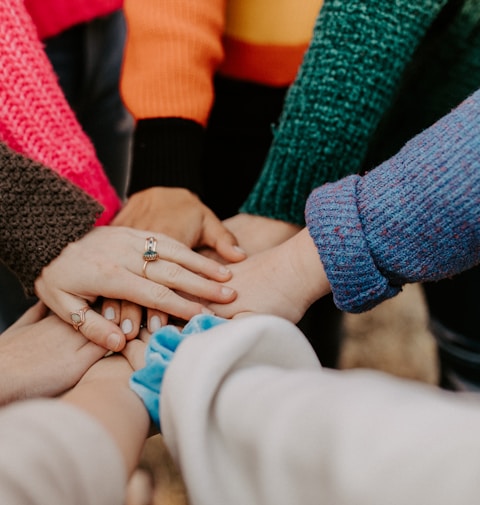 person in red sweater holding babys hand