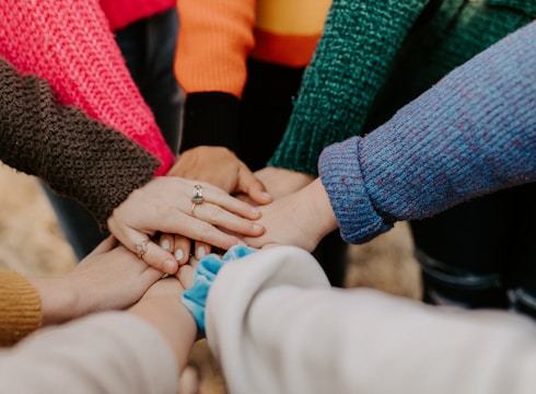 person in red sweater holding babys hand